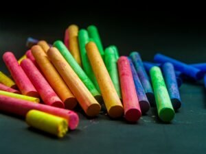 A collection of colorful chalk sticks arranged on a black surface, perfect for artistic and educational themes.