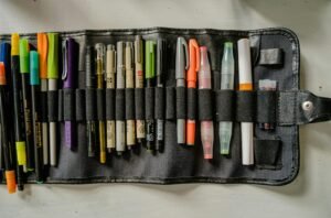 A variety of art pens and markers organized in a black foldable case, perfect for creatives.