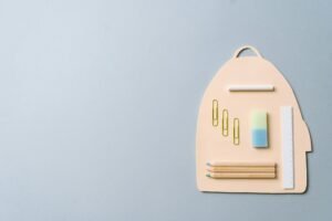 Minimalist top view of school supplies creatively arranged on a backpack-shaped platform.
